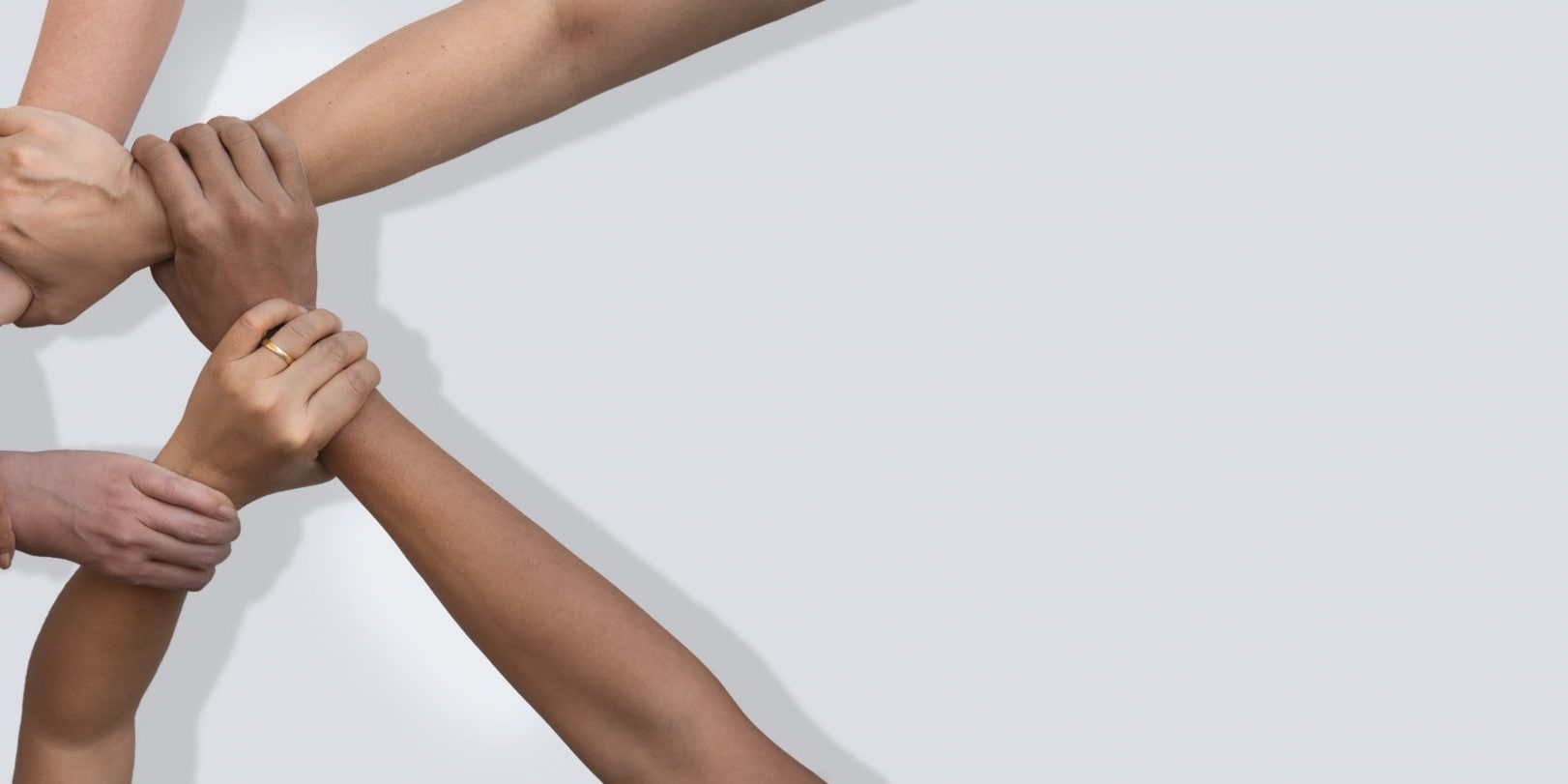 Business people united hands together in teamwork on white background with copy space for header.